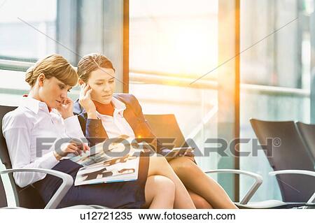 Stock Photography - Portrait of young attractive airport staffs talking and sitting while on break in airport. Fotosearch