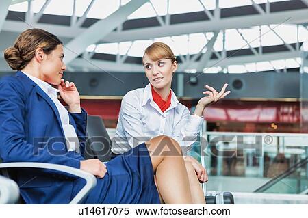 Stock Photography - Portrait of young attractive airport staffs talking and sitting while on break in airport. Fotosearch
