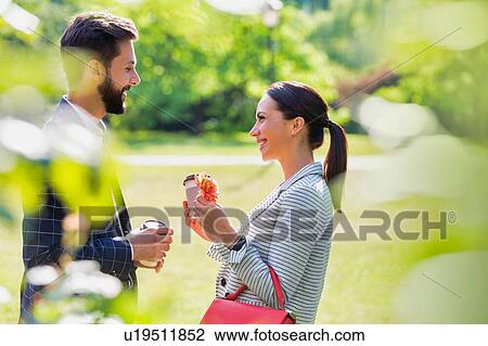 Stock Image - Portrait of young attractive business couple dating in park during break. Fotosearch