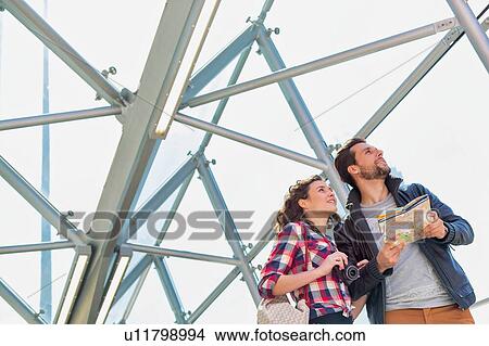 Picture - Portrait of young attractive couple looking on the map in the middle of the city. Fotosearch