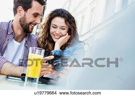 Portrait of young attractive couple walking while eating ice cream with lens flare in background View Large Photo Image Picture - Portrait of young attractive couple walking while eating ice cream with lens flare in background. Fotosearch