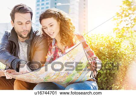 Portrait of young attractive couple sitting while looking on the map with lens flare in background View Large Photo Image Stock Image - Portrait of young attractive couple sitting while looking on the map with lens flare in background. Fotosearch