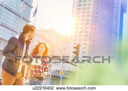 Portrait of young attractive couple walking in the middle of the city with lens flare in background View Large Photo Image Stock Image - Portrait of young attractive couple walking in the middle of the city with lens flare in background. Fotosearch