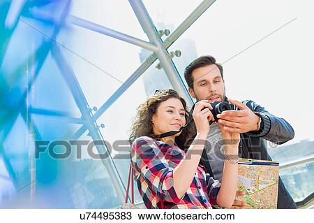 Stock Image - Portrait of young attractive couple looking on their pictures in the camera. Fotosearch