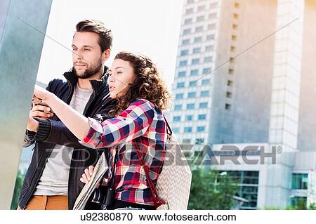 Portrait of young attractive couple looking at the monitor with lens flare in background View Large Photo Image Stock Image - Portrait of young attractive couple looking at the monitor with lens flare in background. Fotosearch