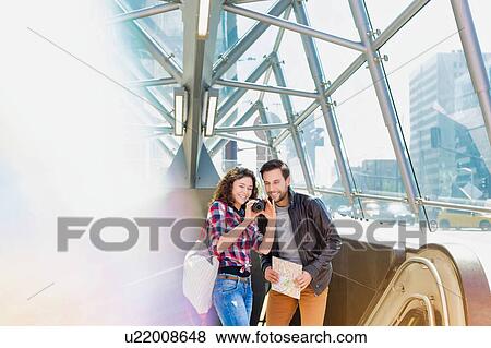 Stock Photo - Portrait of young attractive couple looking on their pictures in the camera. Fotosearch