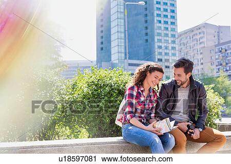 Stock Image - Portrait of young attractive happy couple sitting in the middle of the city. Fotosearch