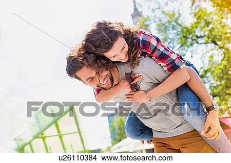 Portrait of young attractive man giving his girlfriend piggy ride back View Large Photo Image Picture - Portrait of young attractive man giving his girlfriend piggy ride back. Fotosearch