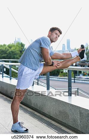 Picture - Portrait of young attractive man stretching his legs. Fotosearch