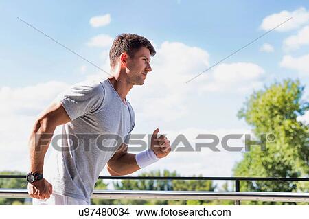 Picture - Portrait of young attractive man running in park. Fotosearch