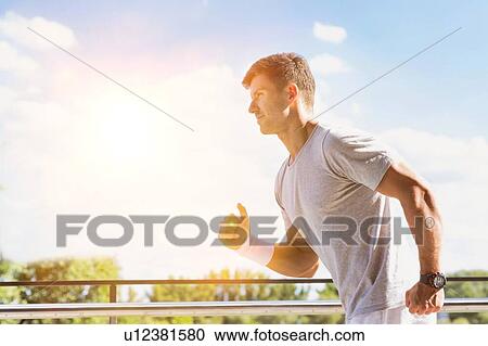 Stock Image - Portrait of young attractive man running in park. Fotosearch