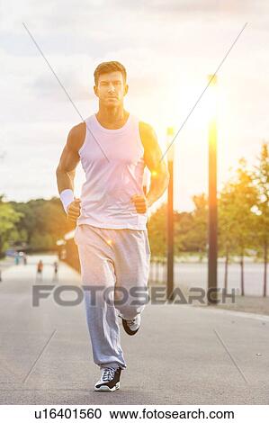 Stock Image - Portrait of young attractive man running in park. Fotosearch