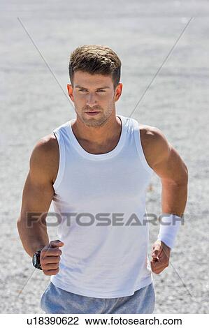 Stock Image - Portrait of young attractive man running in park. Fotosearch