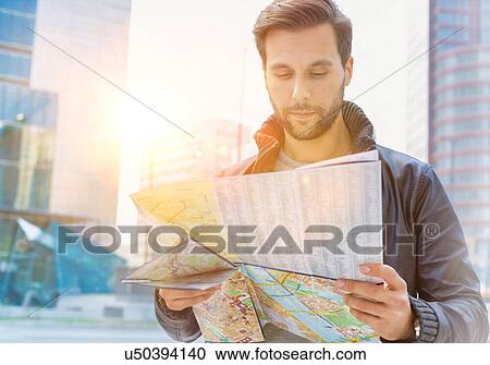 Portrait of young attractive man looking on the map in the city with lens flare in background View Large Photo Image Stock Image - Portrait of young attractive man looking on the map in the city with lens flare in background. Fotosearch
