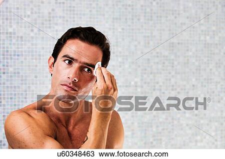 Portrait of young attractive man cleansing his face with cotton and toner in the bathroom View Large Photo Image Stock Image - Portrait of young attractive man cleansing his face with cotton and toner in the bathroom. Fotosearch