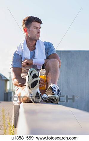 Portrait of young attractive man sitting while drinking energy drink View Large Photo Image Stock Photo - Portrait of young attractive man sitting while drinking energy drink. Fotosearch