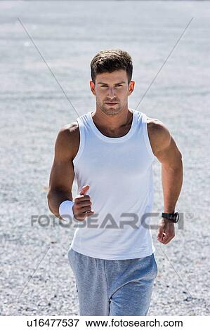 Stock Photo - Portrait of young attractive man running in park. Fotosearch