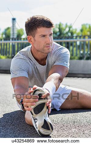 Portrait of young attractive man stretching his legs View Large Photo Image Stock Photo - Portrait of young attractive man stretching his legs. Fotosearch