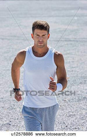 Stock Photograph - Portrait of young attractive man running in park. Fotosearch