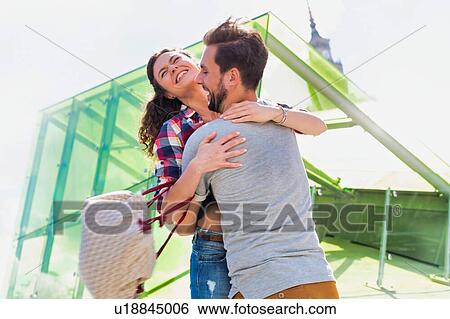 Portrait of young attractive man embracing his girlfriend in the middle of the city View Large Photo Image Stock Photograph - Portrait of young attractive man embracing his girlfriend in the middle of the city. Fotosearch