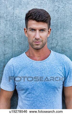 Portrait of young attractive man standing against wall View Large Photo Image Stock Photograph - Portrait of young attractive man standing against wall. Fotosearch