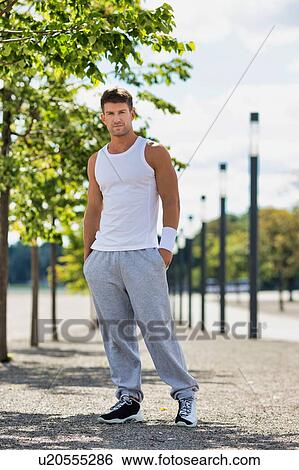 Stock Photograph - Portrait of young attractive man wearing sports wear standing in park. Fotosearch