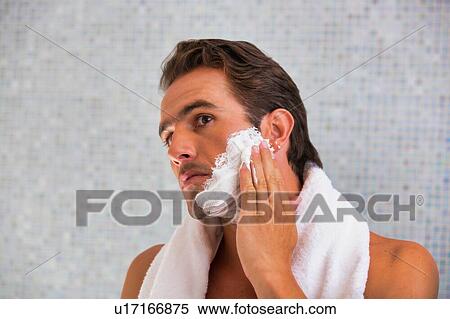 Stock Photography - Portrait of young attractive man applying facial foam in his face . Fotosearch