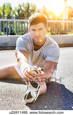 Stock Photography - Portrait of young attractive man stretching his legs. Fotosearch
