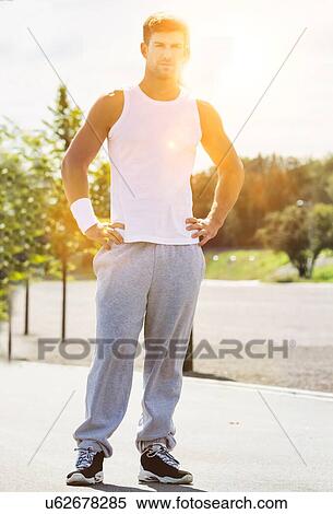 Stock Photography - Portrait of young attractive man wearing sports wear standing in park. Fotosearch