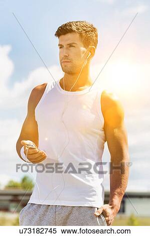 Portrait of young attractive man standing while using and listening to music on his smartphone in park View Large Photo Image Stock Photography - Portrait of young attractive man standing while using and listening to music on his smartphone in park. Fotosearch