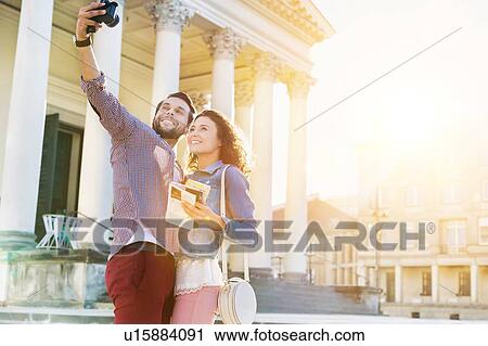 Stock Image - Portrait of young attractive man taking selfie with his girlfriend . Fotosearch