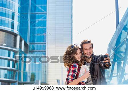 Stock Photo - Portrait of young attractive man taking selfie with his girlfriend in the middle of the city. Fotosearch