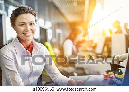 Stock Photo - Portrait of young attractive passenger service agent working in airport with lens flare. Fotosearch