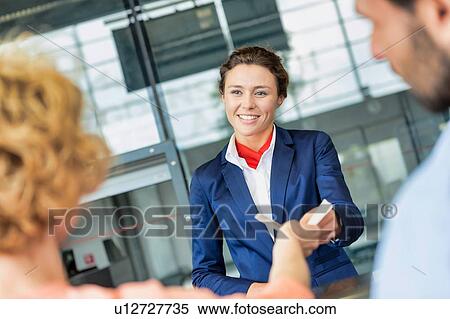 Portrait of young attractive passenger service agent giving boarding with passenger after check in at airport View Large Photo Image Stock Photography - Portrait of young attractive passenger service agent giving boarding with passenger after check in at airport. Fotosearch