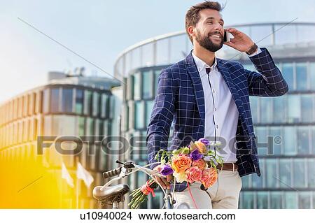 Portrait of young attractive businessman holding boquet of flowers while talking on smartphone View Large Photo Image Picture - Portrait of young attractive businessman holding boquet of flowers while talking on smartphone. Fotosearch