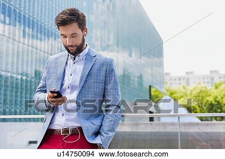 Portrait of young attractive businessman using smartphone with earphones on View Large Photo Image Picture - Portrait of young attractive businessman using smartphone with earphones on. Fotosearch
