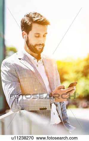 Portrait of young attractive businessman using smartphone with earphones on View Large Photo Image Stock Image - Portrait of young attractive businessman using smartphone with earphones on. Fotosearch