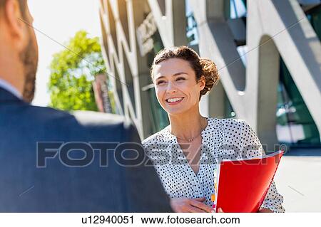 Stock Image - Portrait of young attractive businesswoman smiling while talking to colleague. Fotosearch