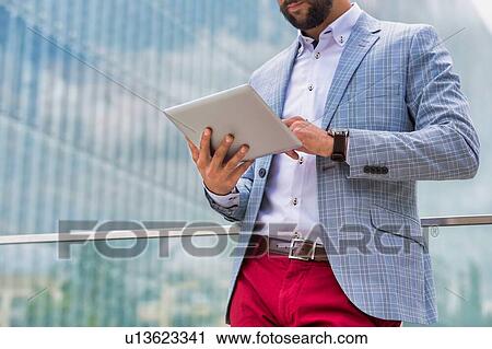 Stock Image - Portrait of young attractive businessman using digital tablet outdoors. Fotosearch