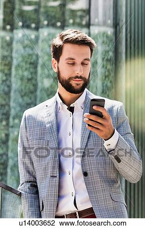 Stock Image - Portrait of young attractive businessman using smartphone. Fotosearch