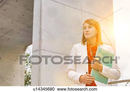 Portrait of young attractive businesswoman standing while holding document View Large Photo Image Stock Image - Portrait of young attractive businesswoman standing while holding document. Fotosearch