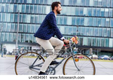 Stock Image - Portrait of young attractive businessman riding bicycle . Fotosearch