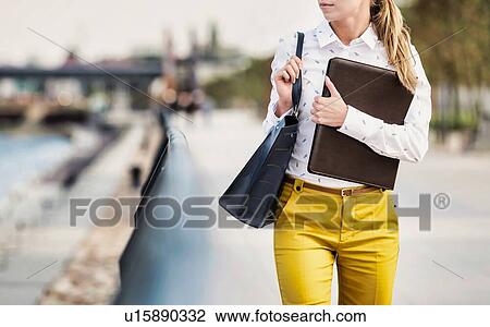 Portrait of Young attractive businesswoman walking while holding document View Large Photo Image Stock Image - Portrait of Young attractive businesswoman walking while holding document. Fotosearch