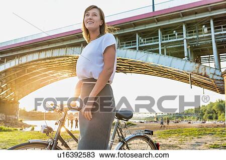 Portrait of young attractive businesswoman holding bicycle while walking under the bridge View Large Photo Image Stock Image - Portrait of young attractive businesswoman holding bicycle while walking under the bridge. Fotosearch
