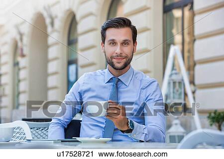 Stock Image - Portrait of young attractive businessman sitting in cafe while drinking coffee . Fotosearch