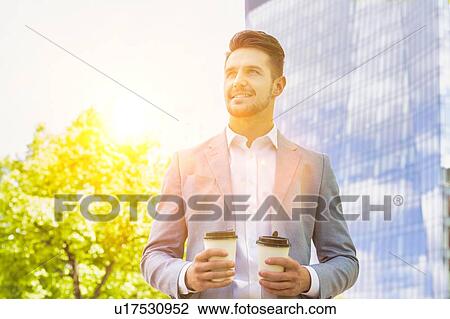 Portrait of young attractive businessman holding two cups of coffee View Large Photo Image Stock Image - Portrait of young attractive businessman holding two cups of coffee . Fotosearch