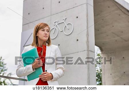 Portrait of young attractive businesswoman standing while holding document View Large Photo Image Stock Image - Portrait of young attractive businesswoman standing while holding document. Fotosearch