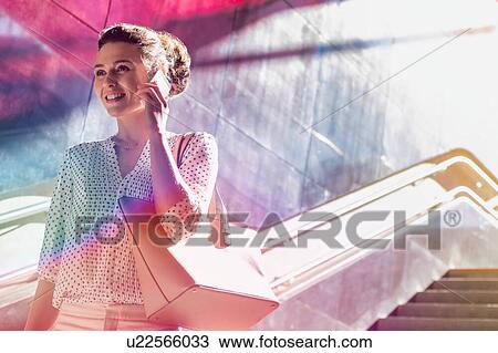 Portrait of young attractive businesswoman talking on smartphone while walking downstairs View Large Photo Image Stock Image - Portrait of young attractive businesswoman talking on smartphone while walking downstairs. Fotosearch