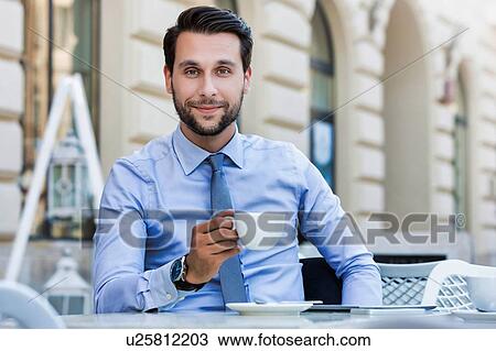 Portrait of young attractive businessman sitting in cafe while drinking coffee View Large Photo Image Stock Image - Portrait of young attractive businessman sitting in cafe while drinking coffee . Fotosearch