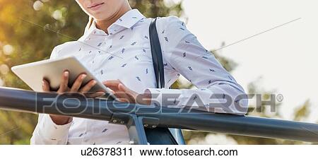 Portrait of young attractive businesswoman using digital tablet while leaning on railing View Large Photo Image Stock Image - Portrait of young attractive businesswoman using digital tablet while leaning on railing. Fotosearch